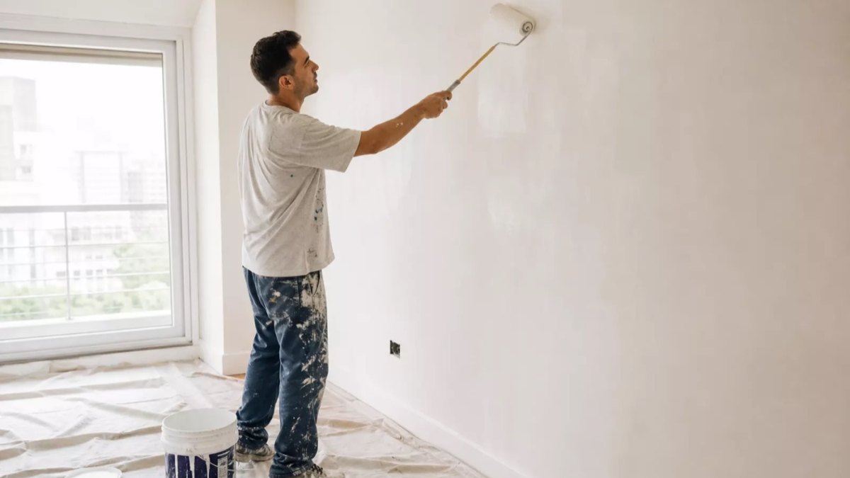 Pintor aplicando látex en pared interior con rodillo